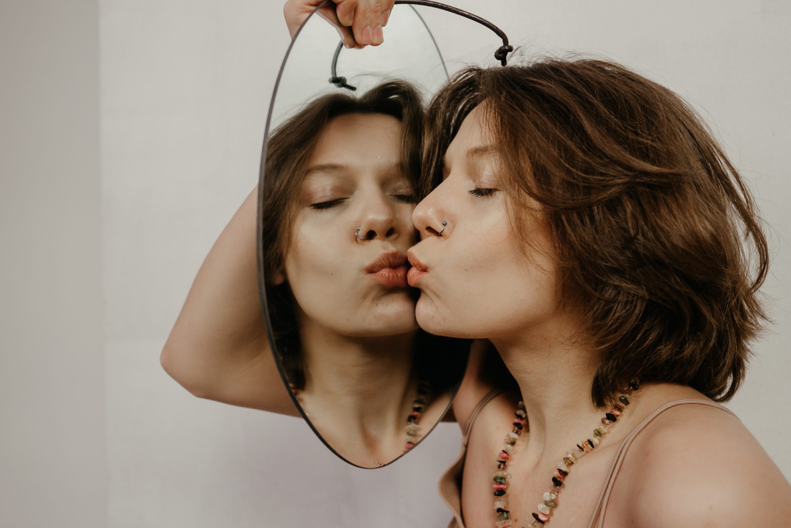 Una mujer se mira en el espejo y se da un beso, transmitiendo amor propio y confianza en sí misma. Una imagen que representa la importancia de la autoestima y el autodescubrimiento