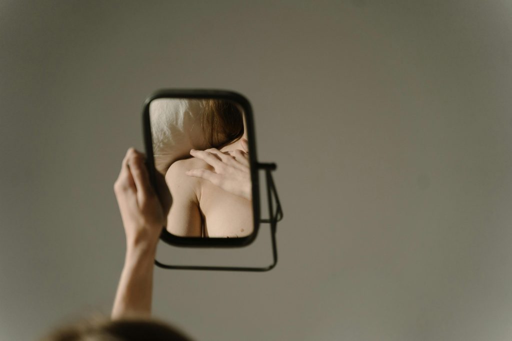 mujer viendo en el espejo y teniendo distorsión cognitiva de su imagen en la conducta alimentaria